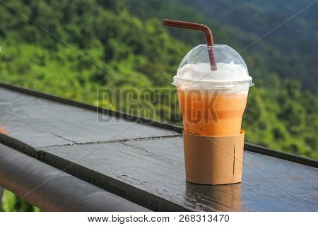 Thai Iced Tea In Plastic Cup With Natual View As Background.