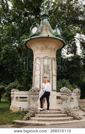 Beautiful Cuple Stand On The Stairs And Hug Each Other. Man And Woman Walking In The Park. Lovestory