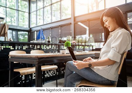 Asian Girl Is Freelancer Woman, She Is Working By Using The Laptop Computer And Driking A Cup Of Cof