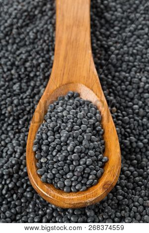 Heap Of Black Organic Beluga Lentils In Wooden Spoon On Black Beluga Lentil Background