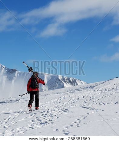 Skier With Skis On His Shoulder Go Up To Top Of Mountain In Cold Sun Day. Winter Caucasus Mountains,