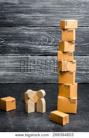 People Stand And Talk Near The Tower Of Cardboard Boxes. Concept Of Business Deal, Sale Of Goods. Se