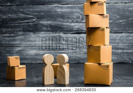 People Stand And Talk Near The Tower Of Cardboard Boxes. Services For The Transportation And Deliver