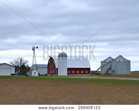 Farm Buildings With Active Windmill On A Cloudy Day In Minnesota - Includes Barn, Granary, Sheds, Be