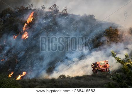 Bulldozer Works With Flames And Smoke On Hillside In Background During California Fire.