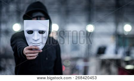 Mystery Hoodie Man With Black Mask Holding White Mask In His Hand. Anonymous Social Masking Or Bipol