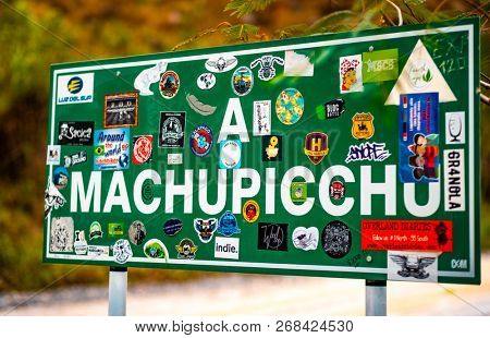 Machupicchu, Peru - 11 october 2018: Big green pointing sign with stickers to Machupicchu on the forest background
