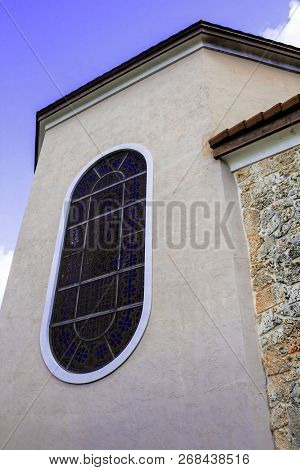 Community Catholic Church Arched Stained Glass Window Corner View With A Blue Sky Background