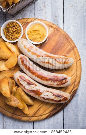 Grilled german sausages with mustard and fried potato chips