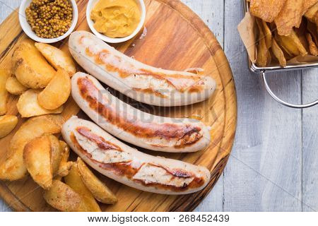Grilled german sausages with mustard and fried potato chips