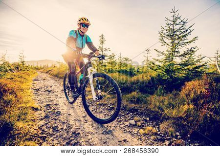 Cycling woman riding on bike in autumn mountains forest landscape. Woman cycling MTB flow trail track. Outdoor sport activity.