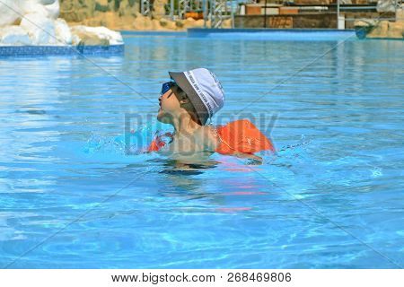 A Boy 7 Years Old Swiming And Playing In A Pool With Resque Rings
