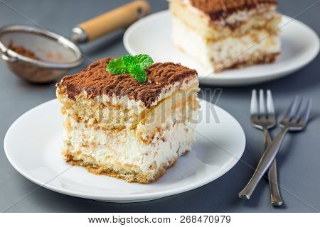Two Piece Of Traditional Italian Tiramisu Dessert Cake On A White Plate, Decorated With Cocoa Powder