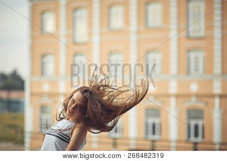 Portrait Of A Girl In Jeans And A T-shirt On The Background Of The Building In The Evening On A Summ