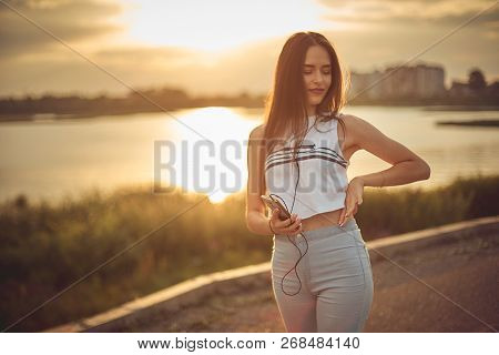 Young Beautiful Caucasian Girl Listening To Music With Smartphone Walking In The City With Headphone