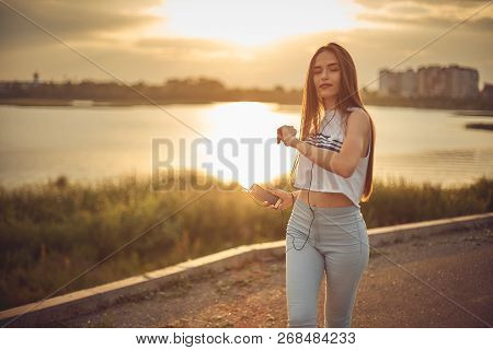 Young Beautiful Caucasian Girl Listening To Music With Smartphone Walking In The City With Headphone