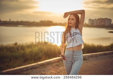 Young Beautiful Caucasian Girl Listening To Music With Smartphone Walking In The City With Headphone