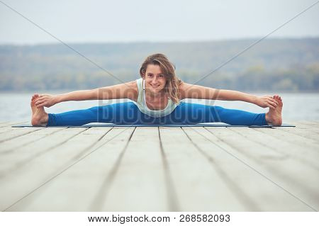 Beautiful Young Woman Practices Yoga Asana Samakonasana - Straight Angle Pose On The Wooden Deck Nea
