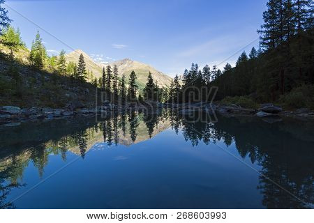 Reflection Of The Shore Of The Lake In The Watery Surface. Early Sunny Morning. The Large (lower) Sh