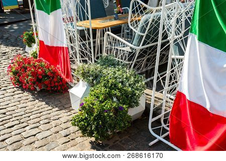 Plants And Flowers In Tubs And Buckets Adorning The Facade Of A Public Place