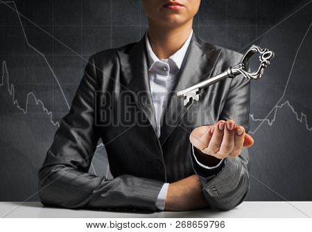 Cropped Image Of Businessman In Suit Keeping Big Key In Hand With Business Sketches On Dark Wall On 
