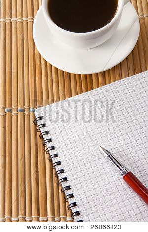 penna su notebok e tazza di caffè sulla paglia