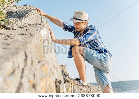 Male Hiker Climbing Up Mountain Cliff During Hiis Travel