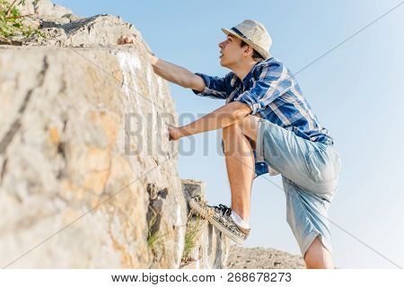 Male Hiker Climbing Up Mountain Cliff During Hiis Travel