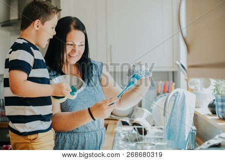 Mother teaching son how to do the dishes