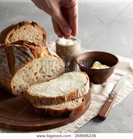 Woman's Hand Sprinkling Sugar Artisan Sliced Toast Bread With Butter On Wooden Cutting Board