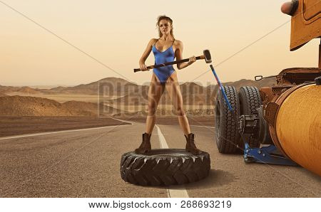 Beautiful woman trucker replace tire on wheel on road 