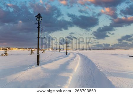 Snow covered pathway along a frozen waterfront.