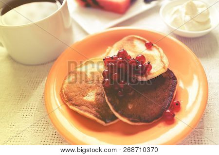 Three Pancakes In Orange Plate And Glass Of Sourcream With Red Berries, Slice Of Watermelon, Wooden 