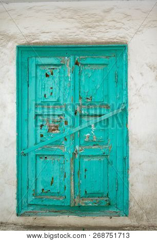 Old Wooden Shutters Of Turquoise Color, Paint Cracked, Closed With An Iron Crossbar. Background, Whi