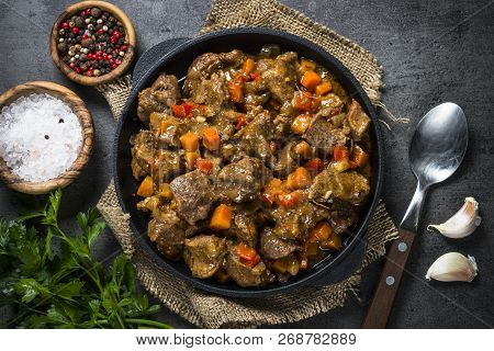 Beef Stew With Vegetables In Iron Pan On Black Background. European Cuisine. Top View.