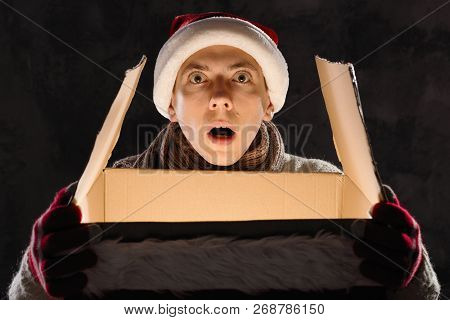 Christmas Gift Concept. Man In Santa Hat Bring Gift For You. Attractive Man Hold Box.  Christmas And