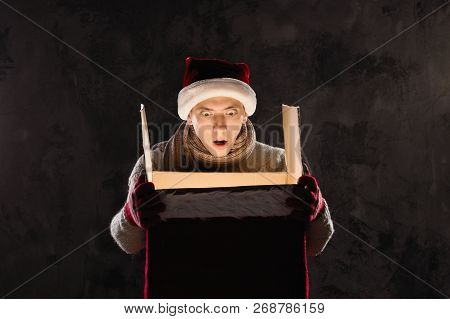 Christmas Gift Concept. Man In Santa Hat Bring Gift For You. Attractive Man Hold Box.  Christmas And