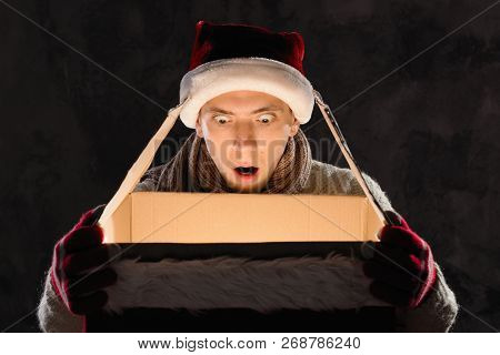 Christmas Gift Concept. Man In Santa Hat Bring Gift For You. Attractive Man Hold Box.  Christmas And