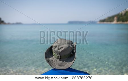 Tourist Wearing A Hat Standing On A Beach And Looking At The Stunning Croatian Coast In Dubrovnik