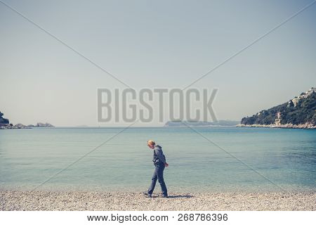 Blond Caucasian Female Tourist Walking Slowly On The Beach And Admiring The Stunning Croatian Coast 