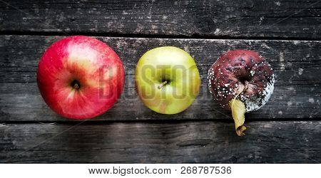 Rotten and healthy apple on wooden table.