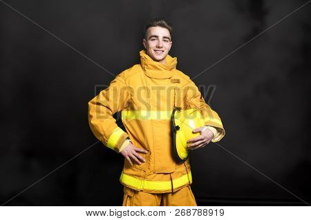 Portrait Of The Fireman Standing Waist Up Studio Shot On Black Background And Moke.