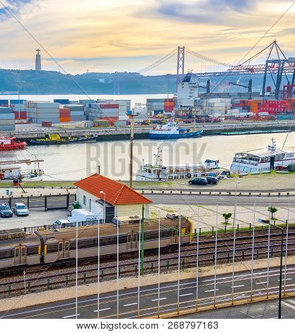 Train On Railroad By Comercial Port With Ships And Containers, 25 De Abril Bridge Over Tagus River A