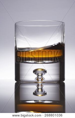 Low Ball Glass On Gray Background With Moving Whiskey Inside