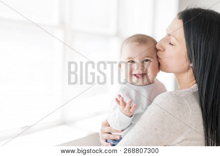 Mother Holds Baby On A Beautiful Room With White Window