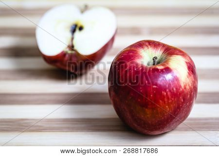 Red Apple Next To Slices Of Another Apple.