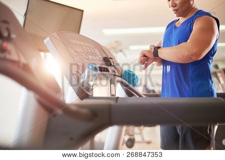 Fit Man Checking Fitness Tracker After Jogging On Threadmill