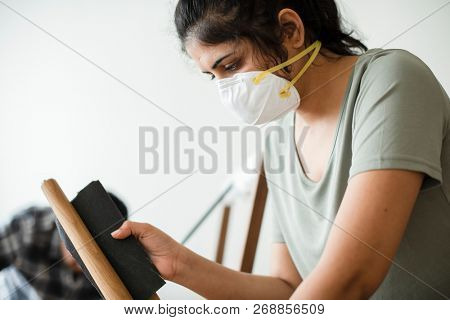 Woman smoothening a wooden table leg
