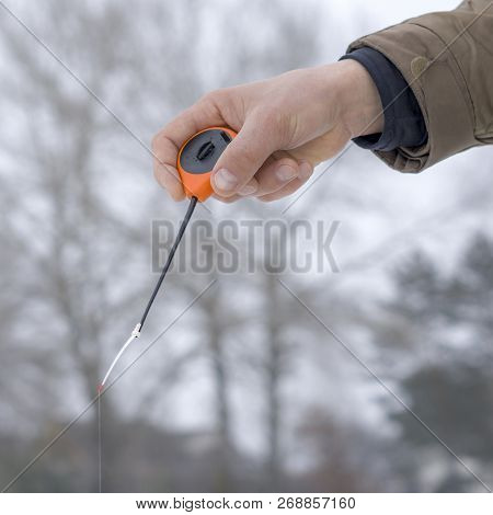 Winter Fishing Concept. Hand Of Fisherman With Specialised Rod Above Snowy Ice.