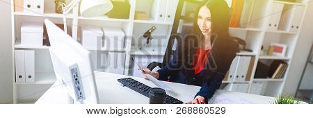 Beautiful Young Girl Works With Documents, Computer And Calculator, Sitting On A Chair In The Office